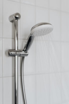 A close up photo of a bathroom shower head with with water coming out of it.